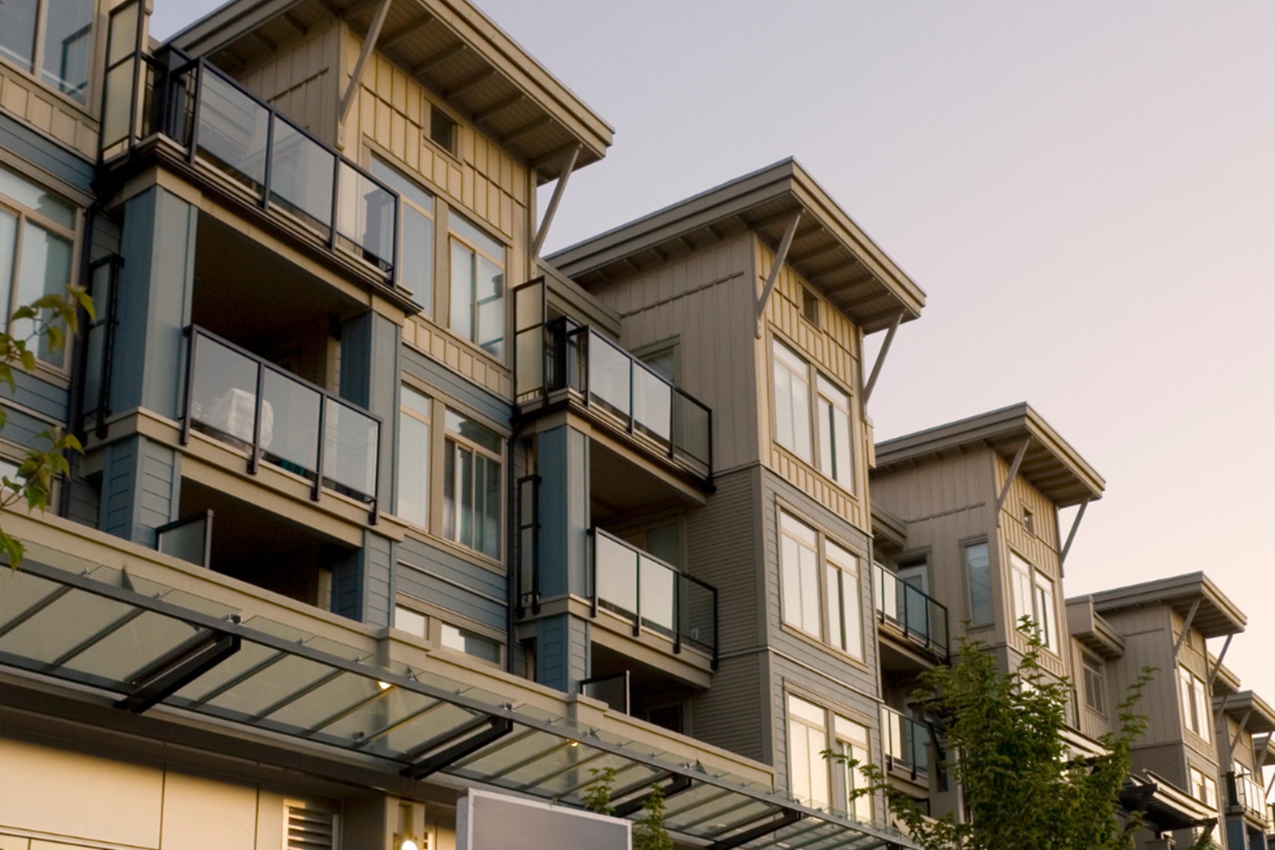 Modern multi-story apartment building with glass balconies and beige siding - https://www.mysoutherninsurance.com/