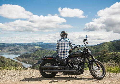 A person in a plaid shirt and helmet sits on a black motorcycle - www.mysoutherninsurance.com